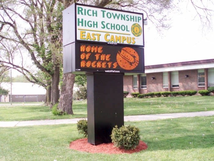 A tall digital sign outside of a school, representing how one can benefit from calling an Orland Park digital sign company.