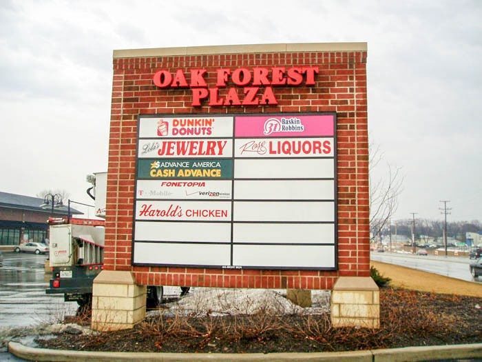 A monument sign with the names and logos of businesses in a parking lot, representing how one can benefit from calling a Tinley Park sign company.