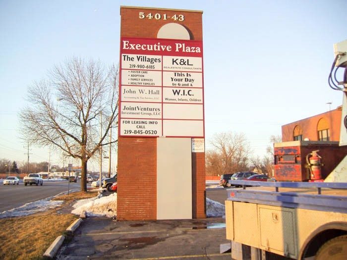 A large, monument sign with the names and logos of businesses in a parking lot, representing how one can benefit from calling a Chicago sign company.