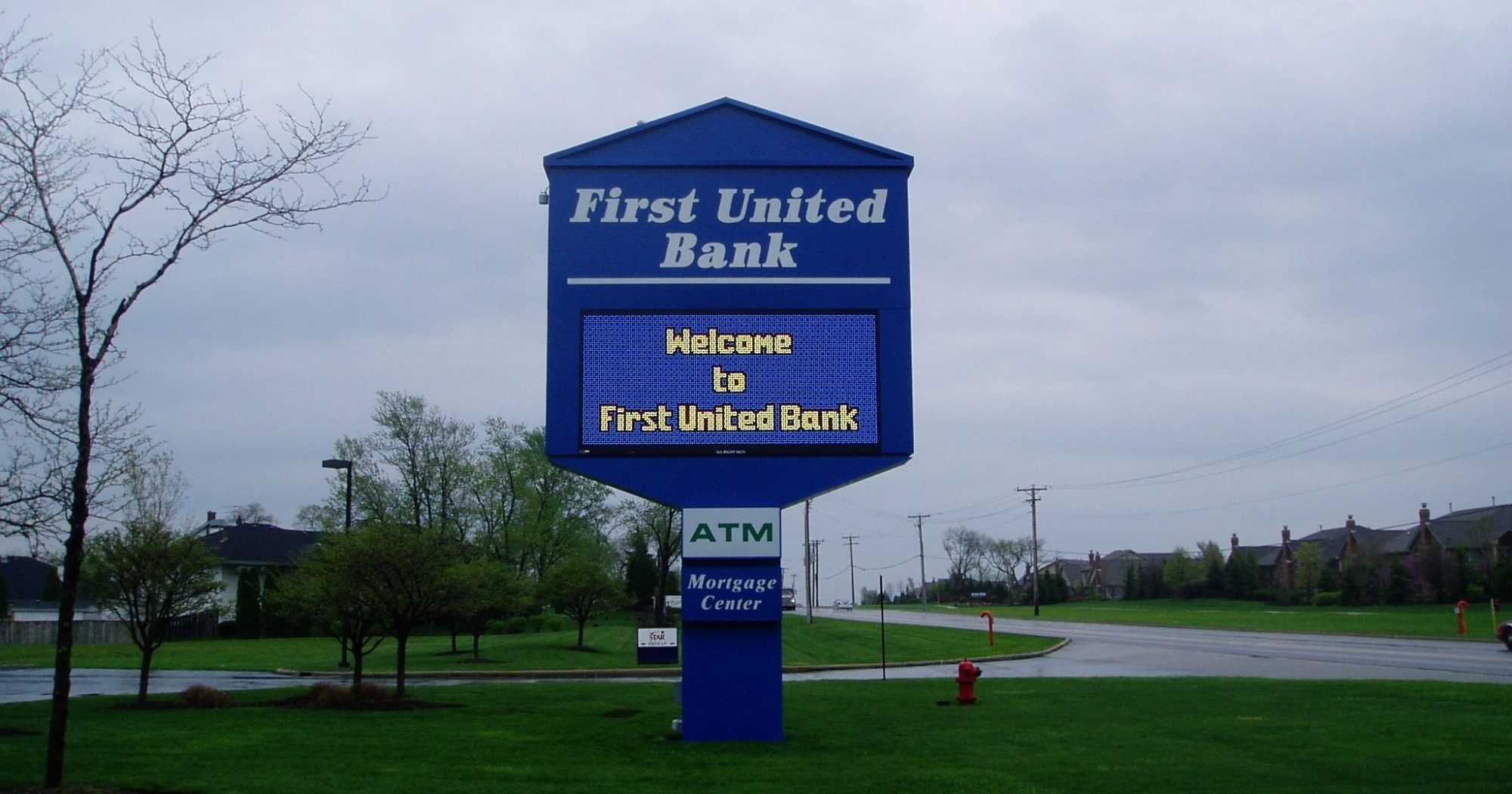 A large, blue, monument, digital sign for a bank in a parking lot, representing how one can benefit from calling a Chicago sign company.