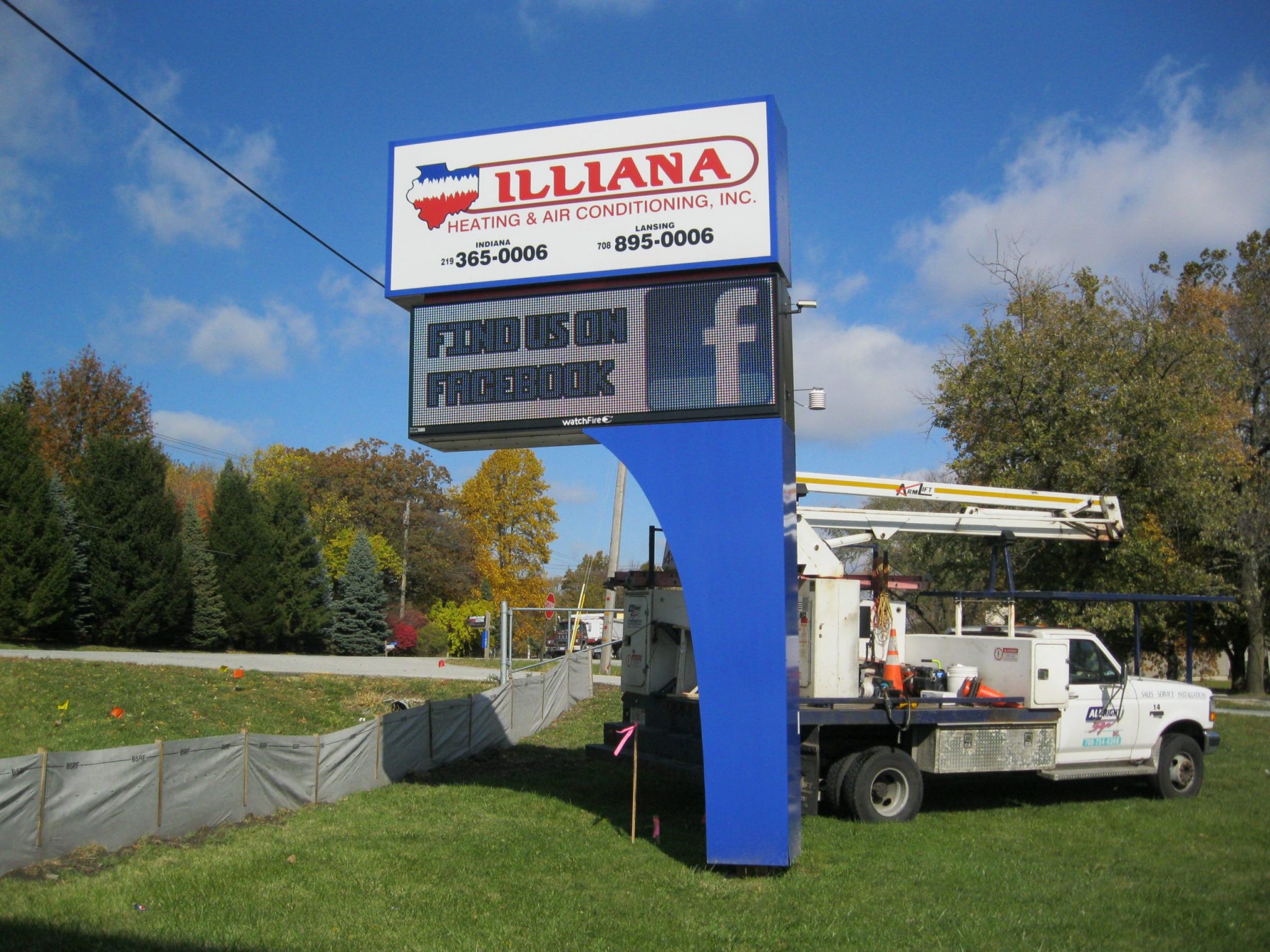 A large, blue, digital sign in a grassy area, representing how one can benefit from calling a Joliet digital sign company.