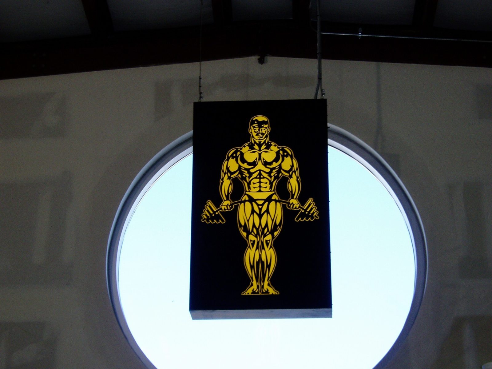 An indoor sign of a golden man lifting a barbell, representing how one can benefit from calling a sign company in Joliet.