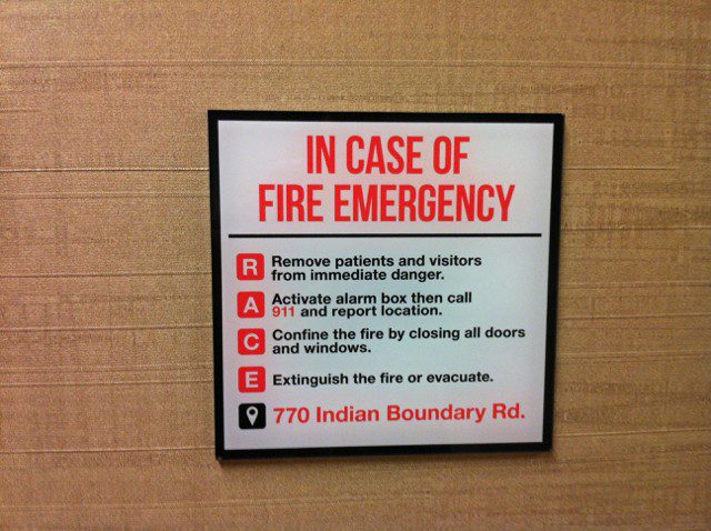 An interior sign with red and black letters giving instructions on what to do in case of fire, representing how one can benefit from contacting a sing company in Orland Park.
