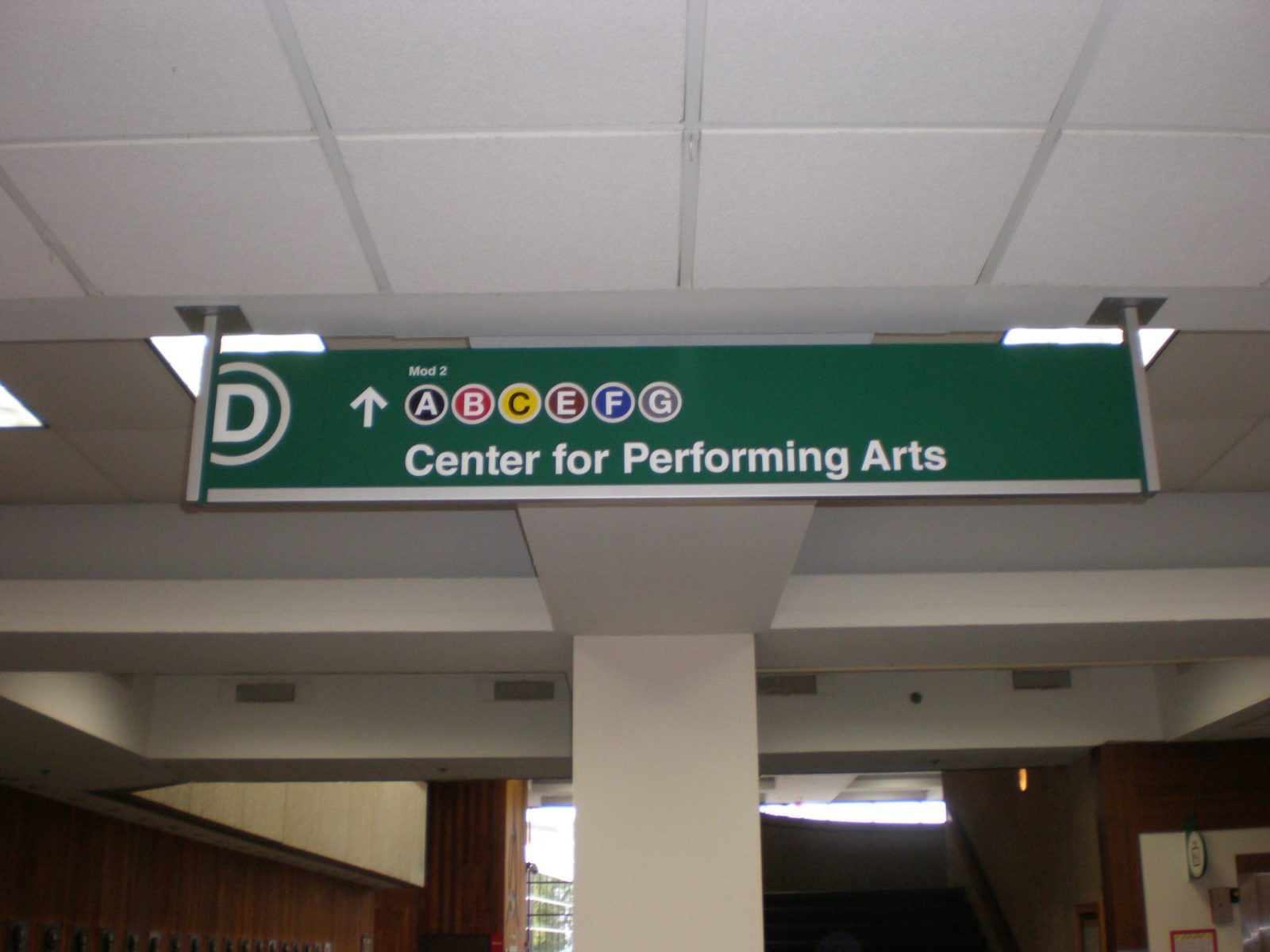 A green, indoor sign coming from the ceiling giving instructions on where to go, representing how one can benefit from calling a sign installation company Highland, IN.