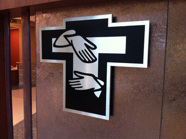 An indoor silver and black sign with two hands, representing how one can benefit from calling an Orland Park sign installation company.