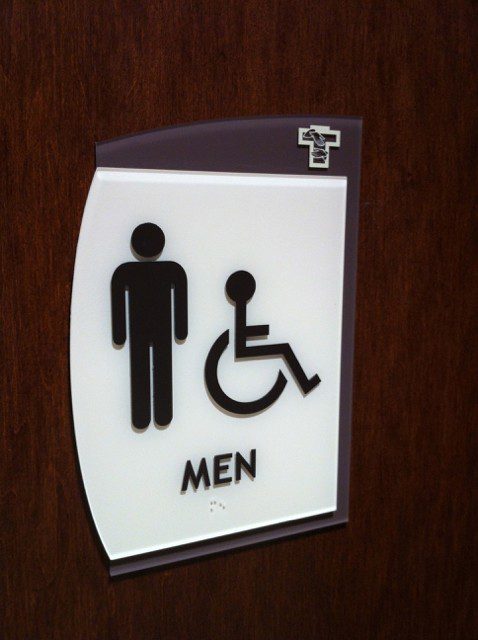 And indoor white sign with a figure of a man and a person in a wheelchair and the word "Men", representing how one can benefit from calling a Plainfield, IL sign company.