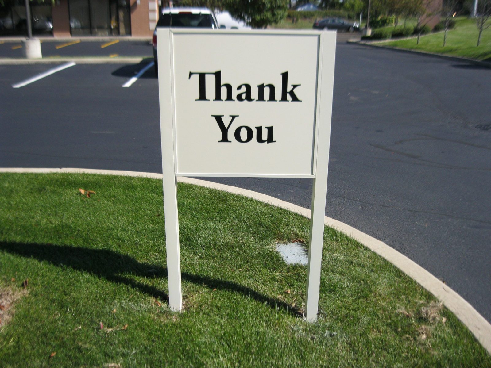 A white panel sign with black letters in a parking lot, representing how one can benefit from calling a Merrillville sign company.