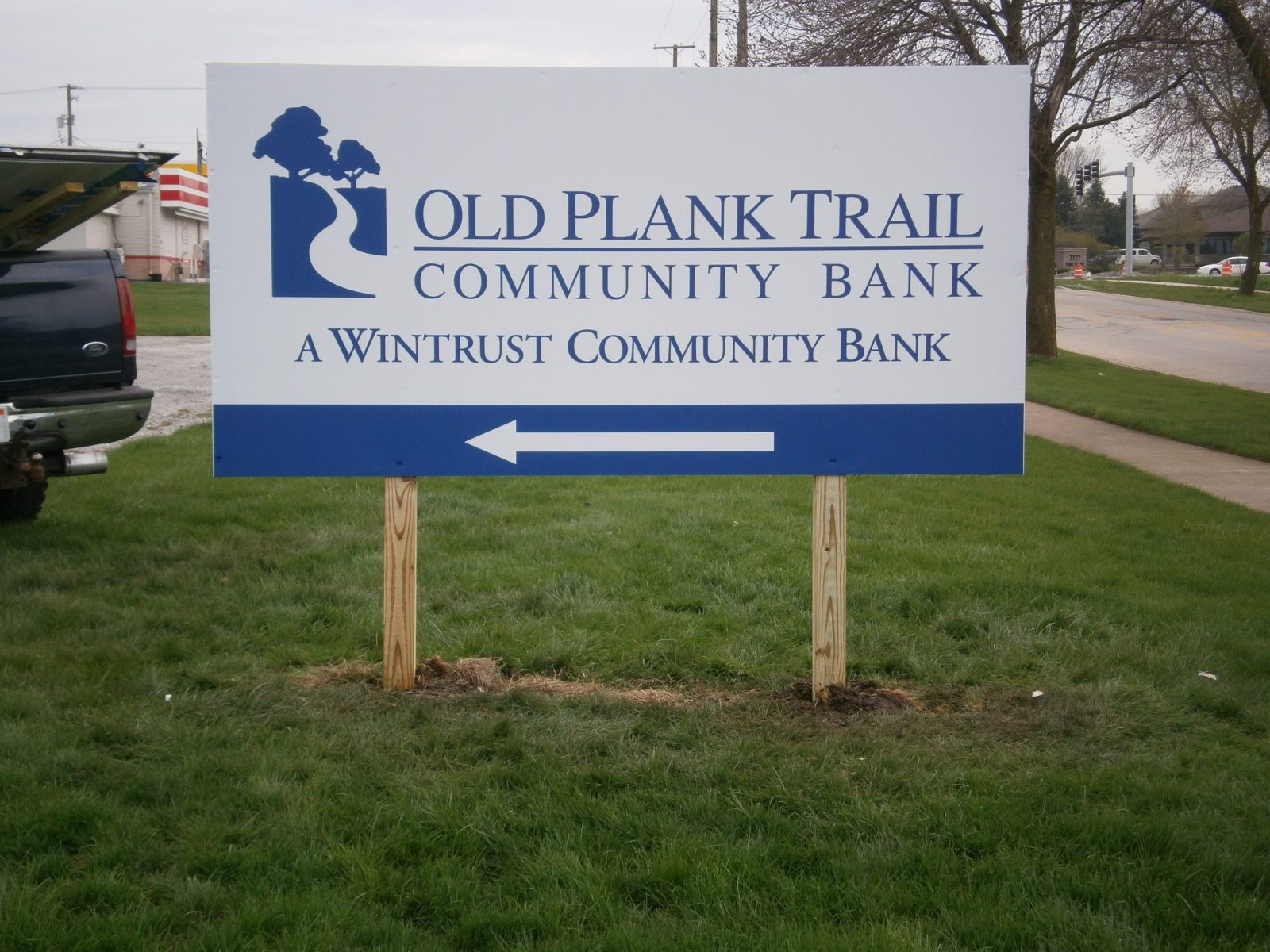 A white and blue panel sign in a grassy area, representing how one can benefit from calling an Orland Park sign company.