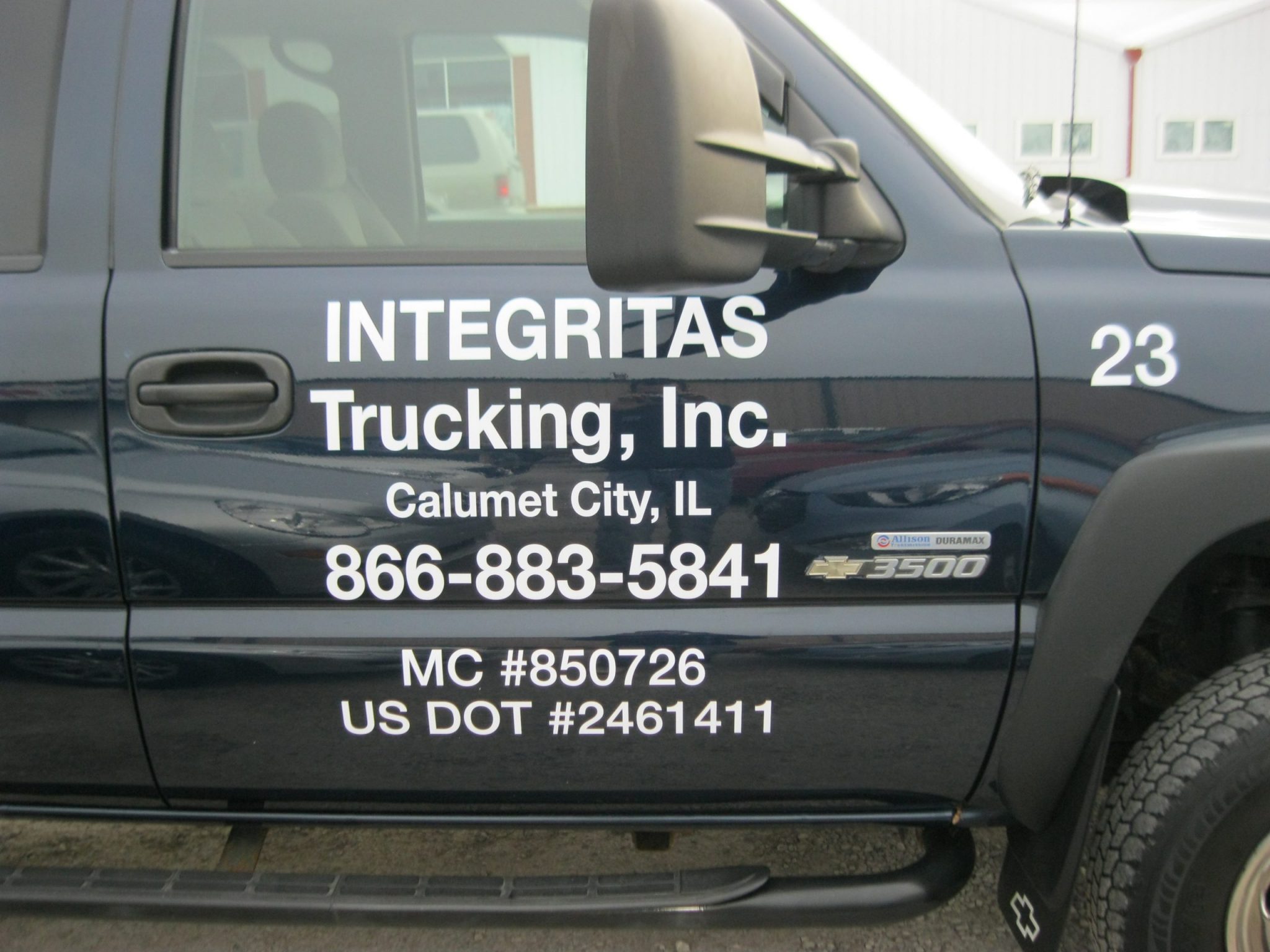 A black truck with white graphic fleet letters, representing how one can benefit from calling a Joliet commercial truck lettering company.