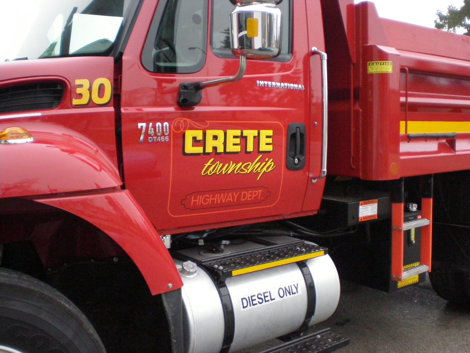 A red commercial truck with yellow graphic fleet, representing how one can benefit from calling a Plainfield, IL commercial truck lettering company.