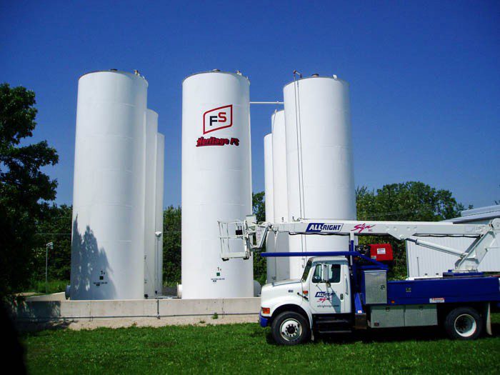 White silos with a big printed graphic with a logo, representing how one can benefit from calling a Tinley Park sign company.