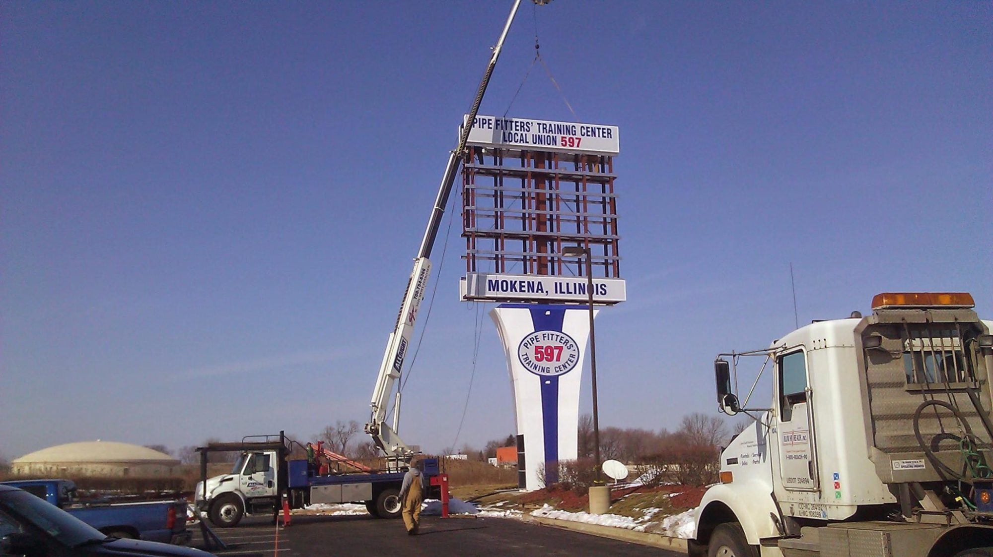 A tall, white sign being installed outside of a business, representing how one can benefit from calling a Joliet sign company.