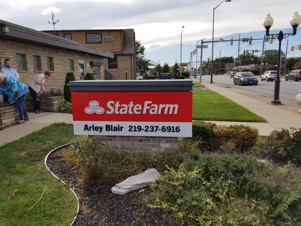 A building outside of a busy street with a red sign that says "State Farm", representing how one can benefit from calling the best Chicago monument sign company.