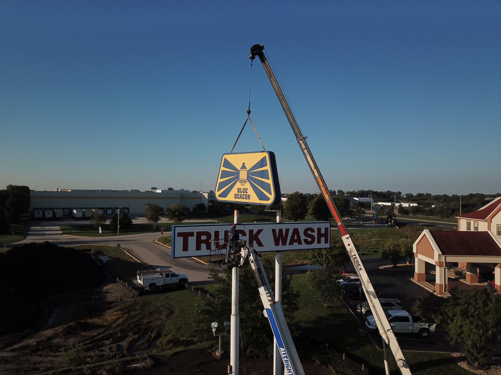 A crane from the Orland Park Sign Company is lifting a sign that says truck wash.